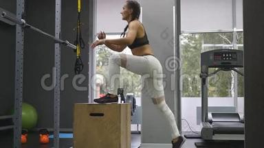 年轻强壮的女人，穿着<strong>运动服</strong>，穿着<strong>运动服</strong>，在健身房里做一套盒子跳跃，动作缓慢。 女孩