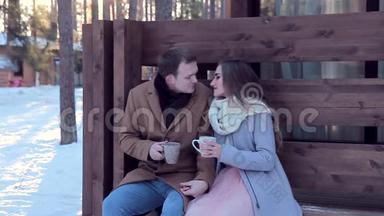 爱的夫妻在冬天的小屋后院喝热茶