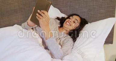 一个女人躺在床上用她的平板电脑在卧室里4K 4K
