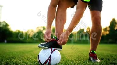 职业足球运动员练习在靴子上系鞋带. 用球特写..
