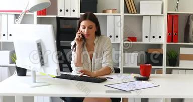 女商人坐在办公室椅子上打电话。
