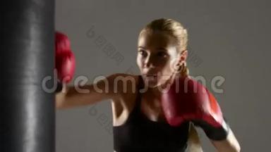 漂亮的女拳击手用拳击袋工作。 格雷工作室