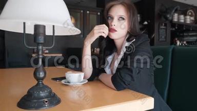 不耐烦，年轻的女人<strong>环顾四周</strong>，在咖啡馆里等人。 布鲁内特正坐在咖啡馆里等着