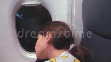 航空飞机概念。 坐在窗边的小女孩睡在飞机上。 晚上乘飞机