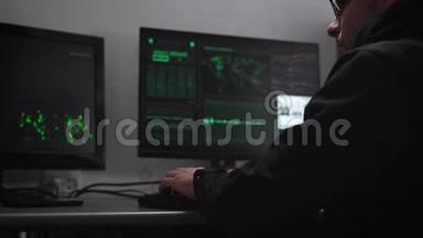 电脑室。 在电脑和桌面键盘上。 黑客试图闯入关键信息。 一个黑暗中的人