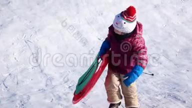 冬天散步的孩子。 一个女孩骑在<strong>塑料板</strong>上的雪滑<strong>板</strong>上。
