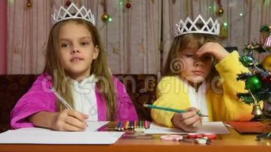 两个穿着睡衣的女孩坐在一张桌子旁，给圣诞老人写了一封信，其中一个认为很有趣