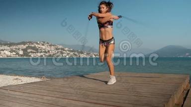 女人用两根跳绳跳，在海滩上做运动。