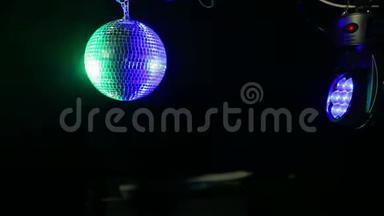 黑色背景上的镜面迪斯科球，用蓝色和绿色<strong>探照灯</strong>射向它