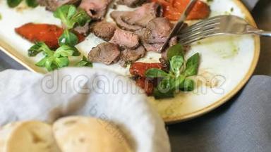 特写拍摄：一盘美味的肉菜，牛肉烤牛肉配甜辣椒和绿色沙拉叶..