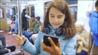 十几岁的女孩带着智能手机和耳机在地铁里，很多人挤在地铁里。 地铁