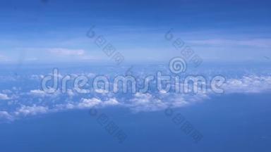 在地平线上明亮的蓝天上的蓬松的云彩。 蓝天白云从窗外的飞机上眺望
