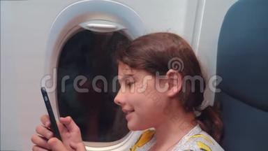 航空飞机概念。 小女孩正坐飞机在窗户旁边聊天，看着里面