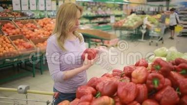 一个女人在一个蔬菜货架上的超市里，买了贝尔胡椒
