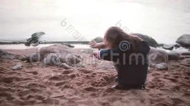 可爱的小女孩坐在岸边<strong>玩沙子</strong>。 她手里拿着<strong>沙子</strong>，然后倒在地上。