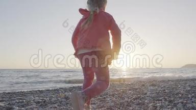 小女孩<strong>跑到</strong>海滩上迎接太阳，高兴地跳起来
