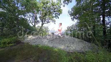 年轻女子正在一座山顶上美丽的异国情调的地方练习瑜伽。 瑜伽和冥想