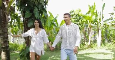 一对在热带花园里手牵手散步的夫妇在户外谈笑风生