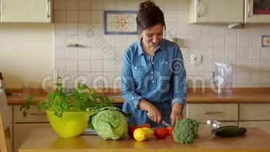 一个年轻的黑发女人正在切蔬菜做沙拉。 他尝试胡萝卜，跳得很有趣。 我们自己做饭。 家庭烹饪