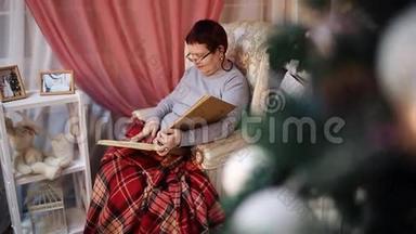 一位戴眼镜的老妇人坐在火炉旁的扶手椅上，翻阅着一张带有照片的相册。 除夕`。