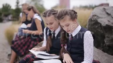 一群年轻的朋友，穿着相同的校服，坐在户外聊天，读一本书。