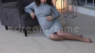 孕妇坐在扶手椅附近。 有灯光的床背景。 美丽的女人在家里度过时光