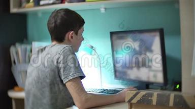 少年在电脑上玩电脑游戏在线策略。 少年在室内玩电脑游戏