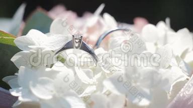 一束白花上的结婚戒指。婚戒和白色和粉色花束的旋转组合