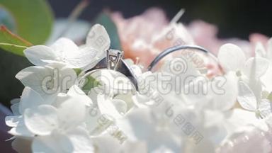一束白花上的结婚戒指。婚戒和白色和粉色花束的旋转组合