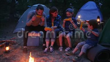 在大自然中野餐，一家人用盐吃<strong>玉米</strong>，去野营，妈妈、爸爸和儿子从外面吃新鲜的<strong>黄色玉米</strong>