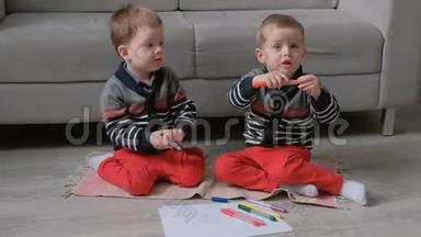两个双胞胎兄弟蹒跚学步的孩子一起画坐在地板上的标记。