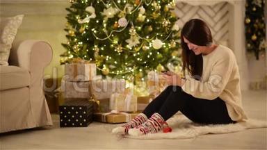 美丽的情感布鲁内特在她的<strong>小东西</strong>上发短信和微笑旁边的大圣诞树和一个盒子与礼物