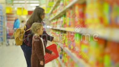 年轻的妻子和<strong>可爱</strong>的女孩站在货架附近的商品在<strong>超</strong>市。 妈妈和孩子一起在果汁店购物