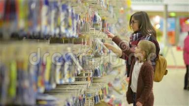 年轻的母亲带着孩子在超市挑选商品。 小女孩用手指指着什么，妈妈