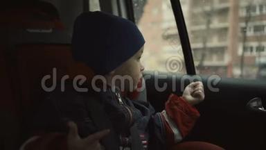 男孩坐在孩子的座位上，在雨天<strong>看着窗外</strong>。