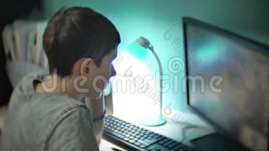 少年在电脑上玩电脑游戏在线策略。 少年在室内玩电脑游戏