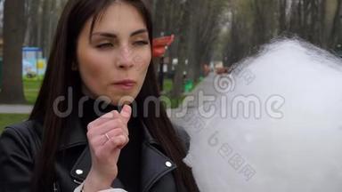 年轻的黑发女人在街上吃棉花糖
