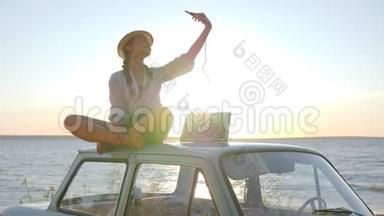 阳光下的汽车照片，女孩坐在屋顶的复古汽车背光做自拍手机
