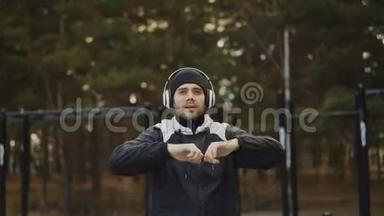 戴耳机的帅哥在冬季公园听<strong>音乐</strong>时做<strong>热身运动</strong>