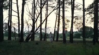 穿着白色衣服的妈妈和女儿在森林附近的田野里走来走去