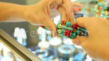 特写。在珠宝店的柜台上，女人的手拿着一个绿松石和<strong>珊瑚色</strong>的手镯。4k，慢动作。
