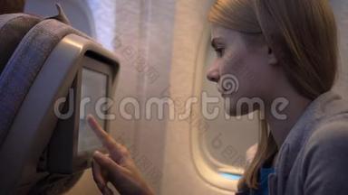 飞机窗户附近美丽迷人的女人。 长途飞行。 使用车载<strong>电视屏幕</strong>