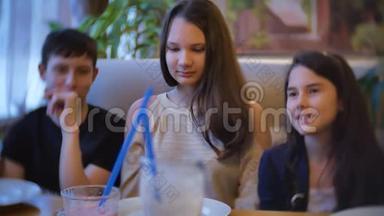 在咖啡馆里交流的女孩是朋友。 儿童青少年坐在咖啡馆快餐室内慢动作视频