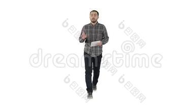 微笑的男人，带着平板走路，在白色的背景上和相机交谈。