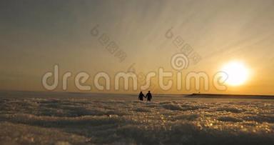 浪漫的年轻夫妇牵着手在海滩上散步，太阳开始下山。