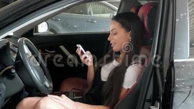 漂亮的年轻女人手里拿着智能手机。 开一辆车。 <strong>商务车</strong>时尚系学生