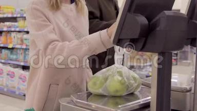在超市里，年轻的女人用电秤称量水果。