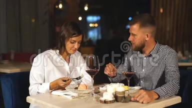 恋爱中的漂亮夫妇正坐在咖啡馆里，喝咖啡，<strong>吃奶</strong>酪蛋糕。 年轻女子正在喂她的男人