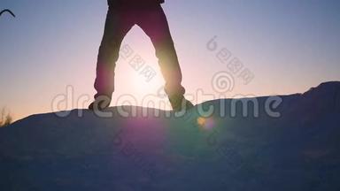 那个家伙在雪坡上跳，在日落时举起双手。雪的<strong>冬天</strong>的风景。 <strong>户外运动</strong>