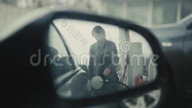 交通和所有权概念-加油站的人在车内加油，从镜子看，下雨天